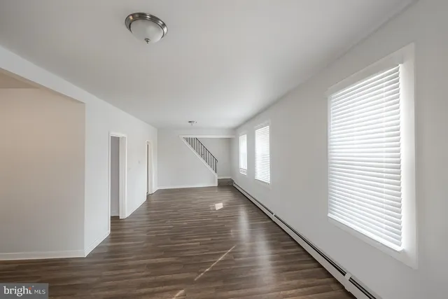 an empty room with wooden floor a fireplace and windows