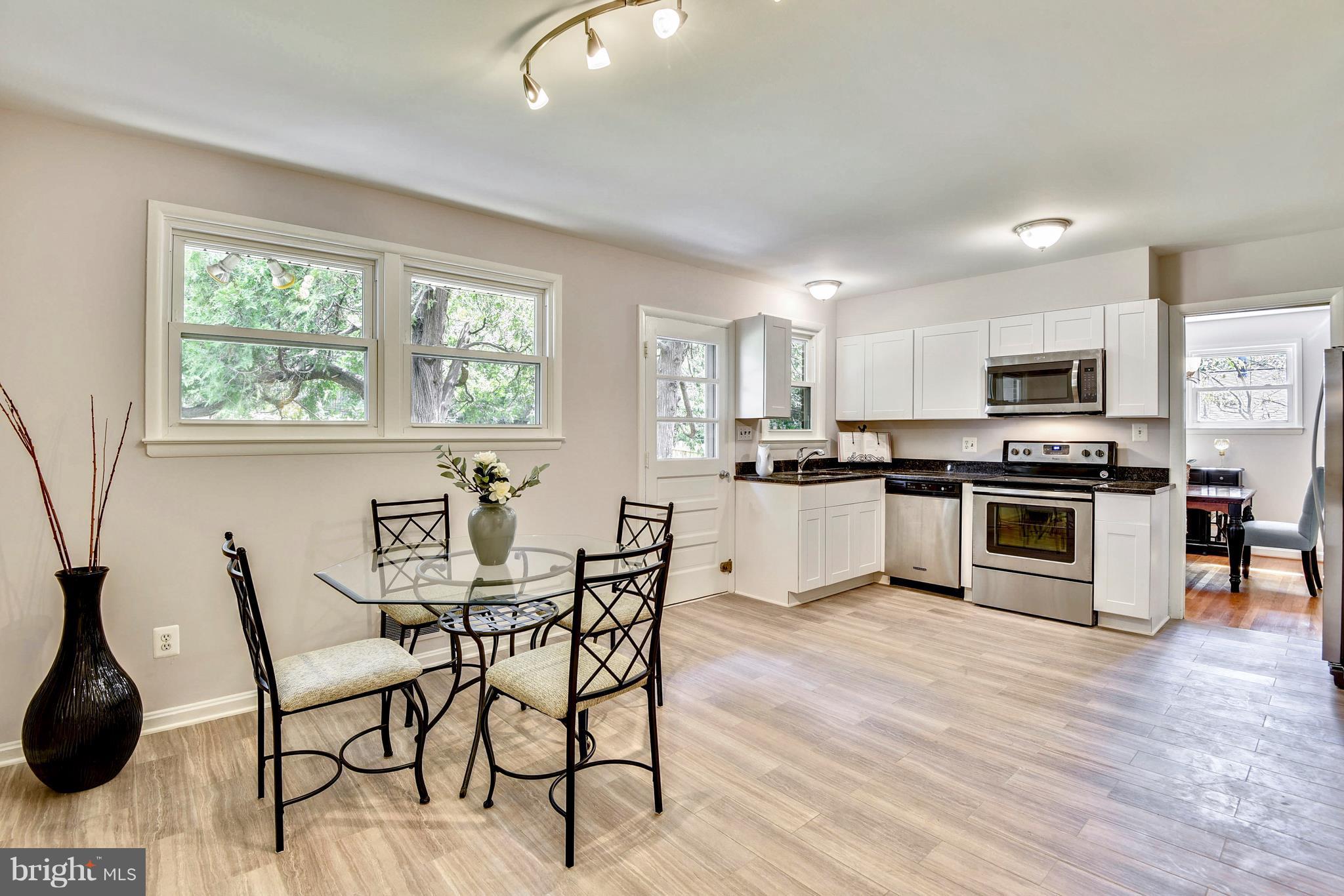 9005 Bradford Road Silver Spring, MD 20901 - Photo 11 of 28 a kitchen with stainless steel appliances a stove a sink a microwave a dining table and chairs