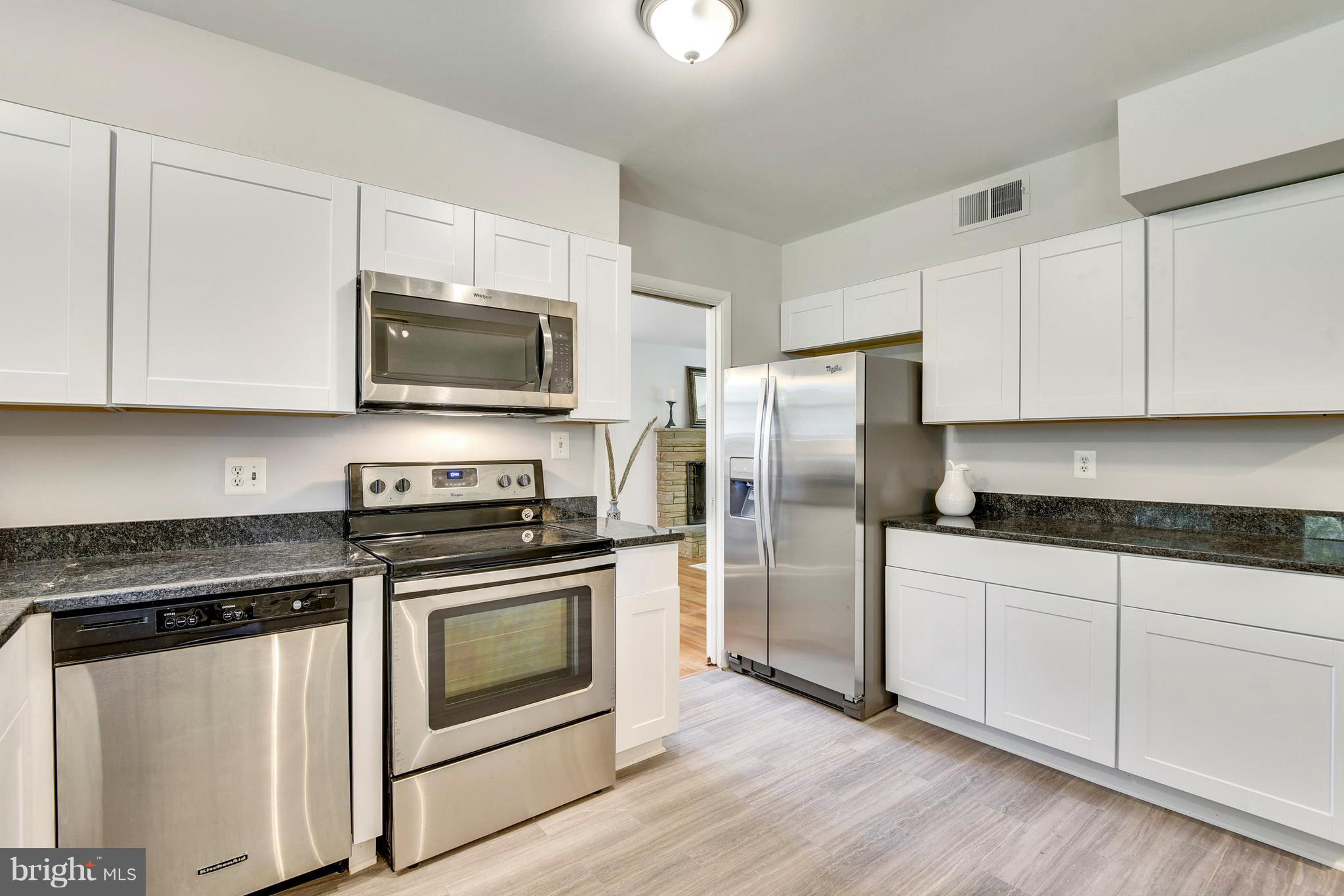 9005 Bradford Road Silver Spring, MD 20901 - Photo 8 of 28 a kitchen with cabinets stainless steel appliances a sink and wooden floor