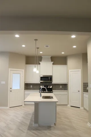 a view of kitchen with granite countertop stove top oven and refrigerator