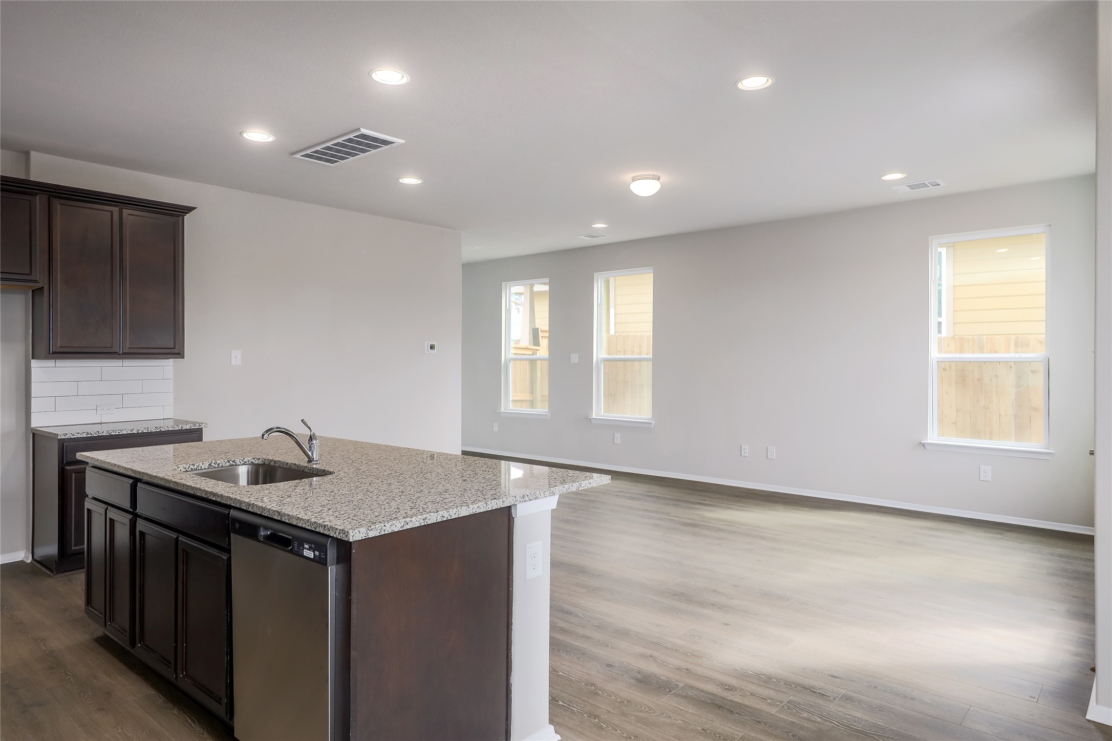 11416 Milano Drive Austin, TX 78747 - Photo 25 of 25 Kitchen featuring dark brown cabinetry, light stone counters, open floor plan, recessed lighting, and tasteful backsplash