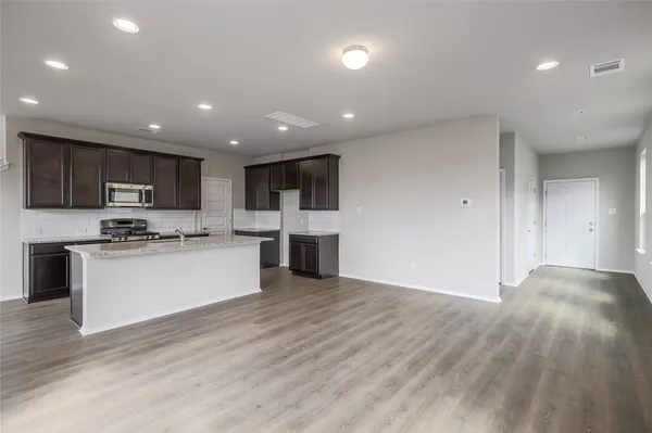 a large kitchen with stainless steel appliances granite countertop a large counter top a sink and a stove