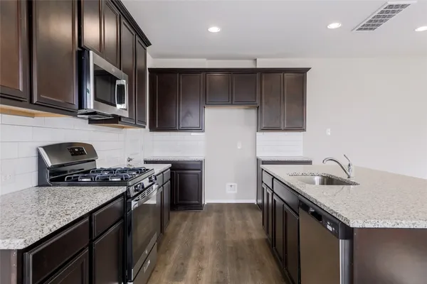 a kitchen with kitchen island granite countertop stainless steel appliances a sink a stove a microwave and cabinets