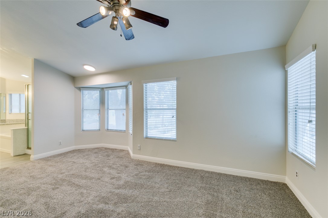 1738 Toltec Circle Henderson, NV 89014 - Photo 8 of 46 A spacious primary bedroom featuring a ceiling fan, plush carpet, and ample natural light.
