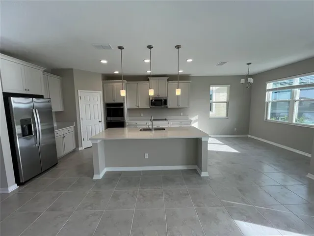 a kitchen with stainless steel appliances kitchen island granite countertop a sink and a refrigerator
