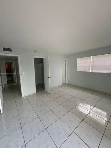 a view of an empty room with window and stairs