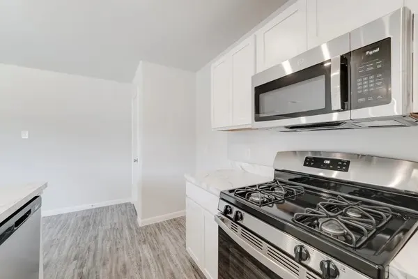 a view of kitchen with stainless steel appliances a sink and wooden floor