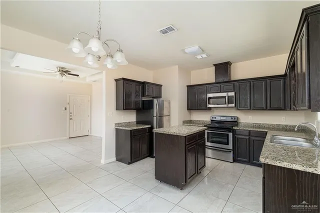 a kitchen with stainless steel appliances granite countertop a sink dishwasher stove top oven and refrigerator
