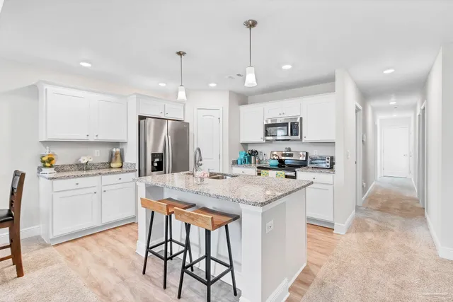 a kitchen with granite countertop stainless steel appliances a refrigerator oven a sink a dining table and chairs