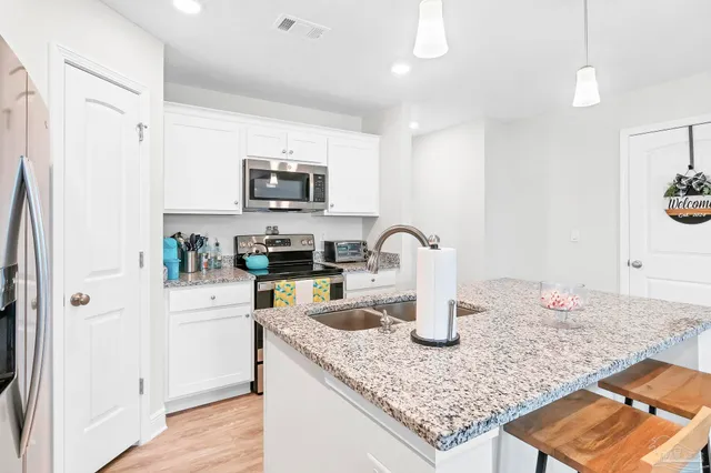 a kitchen with stainless steel appliances white cabinets and a refrigerator