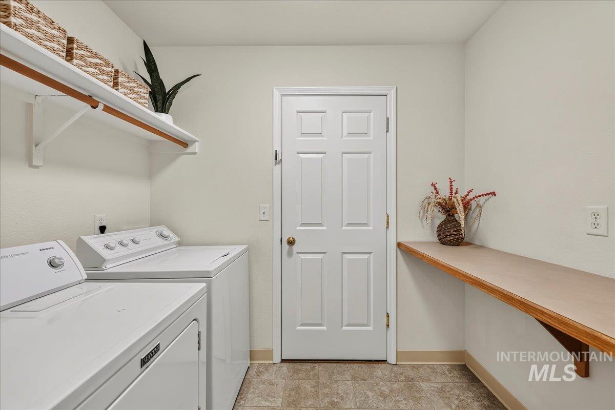 2356 West Hill Road Boise, ID 83702 - Photo 21 of 22 Dedicated laundry area with a white paneled door, durable flooring, integrated shelving, and a mounted folding surface