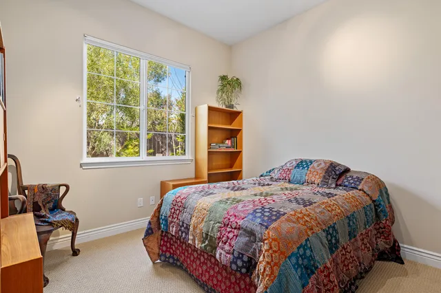 a bedroom with a bed and chair with a window