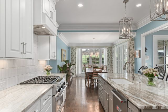 a kitchen with stainless steel appliances granite countertop a dining table chairs refrigerator and cabinets