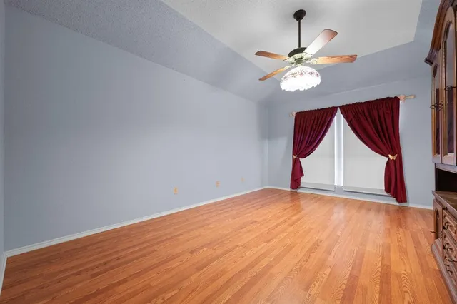 a view of an empty room with window and wooden floor