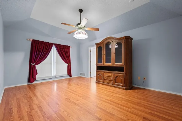 a view of an empty room with wooden floor and window