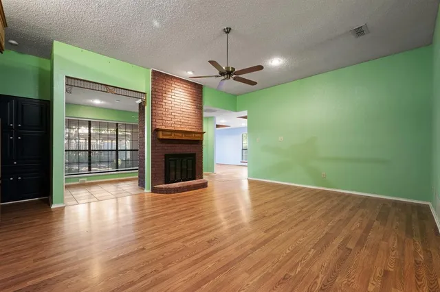 an empty room with wooden floor a ceiling fan and a fireplace