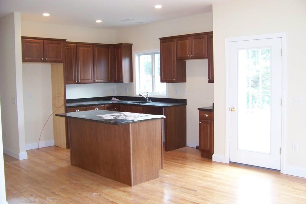 509 Main Street, Unit 4 Old Saybrook, CT 06475 - Photo 5 of 27 a kitchen with kitchen island granite countertop wooden cabinets a refrigerator and a sink