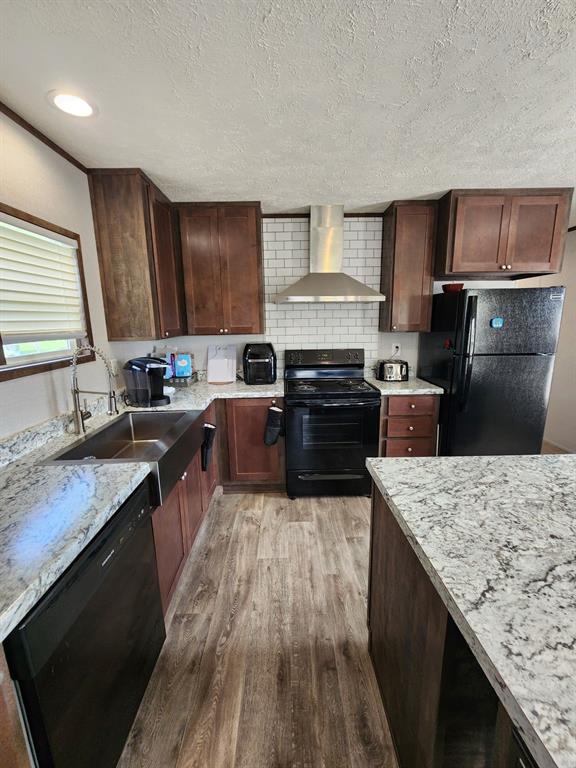 191 Sioux Quitman, TX 75783 - Photo 7 of 23 a kitchen with granite countertop a stove top oven a sink dishwasher and wooden cabinets with wooden floor