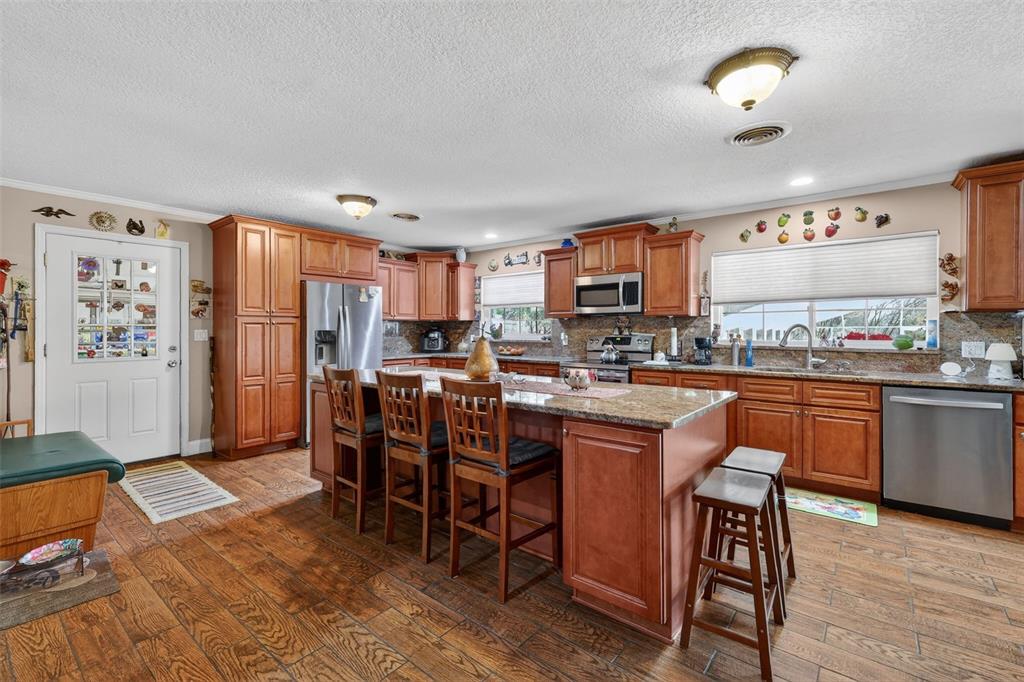 2230 Southwest 87th Place Ocala, FL 34476 - Photo 18 of 42 a kitchen with stainless steel appliances granite countertop a refrigerator a stove a sink a dining table and chairs with wooden floor
