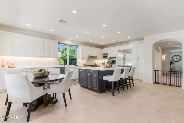 a kitchen with kitchen island granite countertop wooden cabinets dining table and chairs
