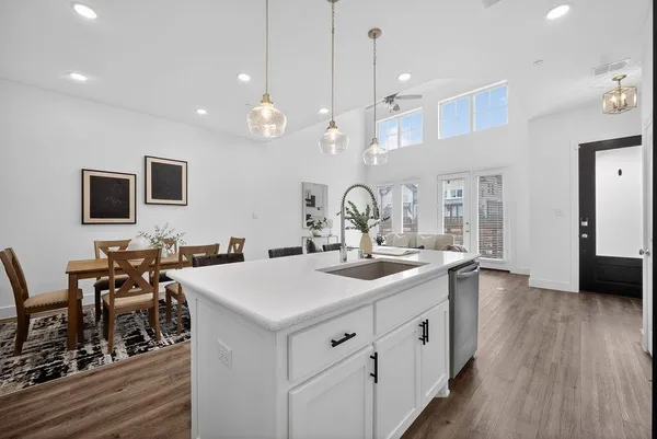 a kitchen with white cabinets a sink dishwasher and a stove with wooden floor