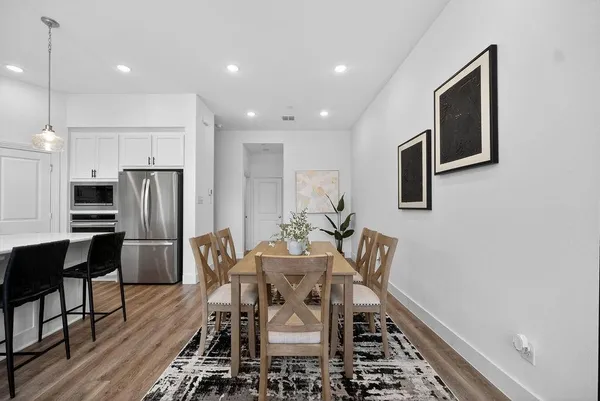 a dining room with stainless steel appliances a dining table and chairs
