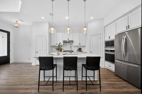 a kitchen with kitchen island granite countertop a table chairs refrigerator and microwave