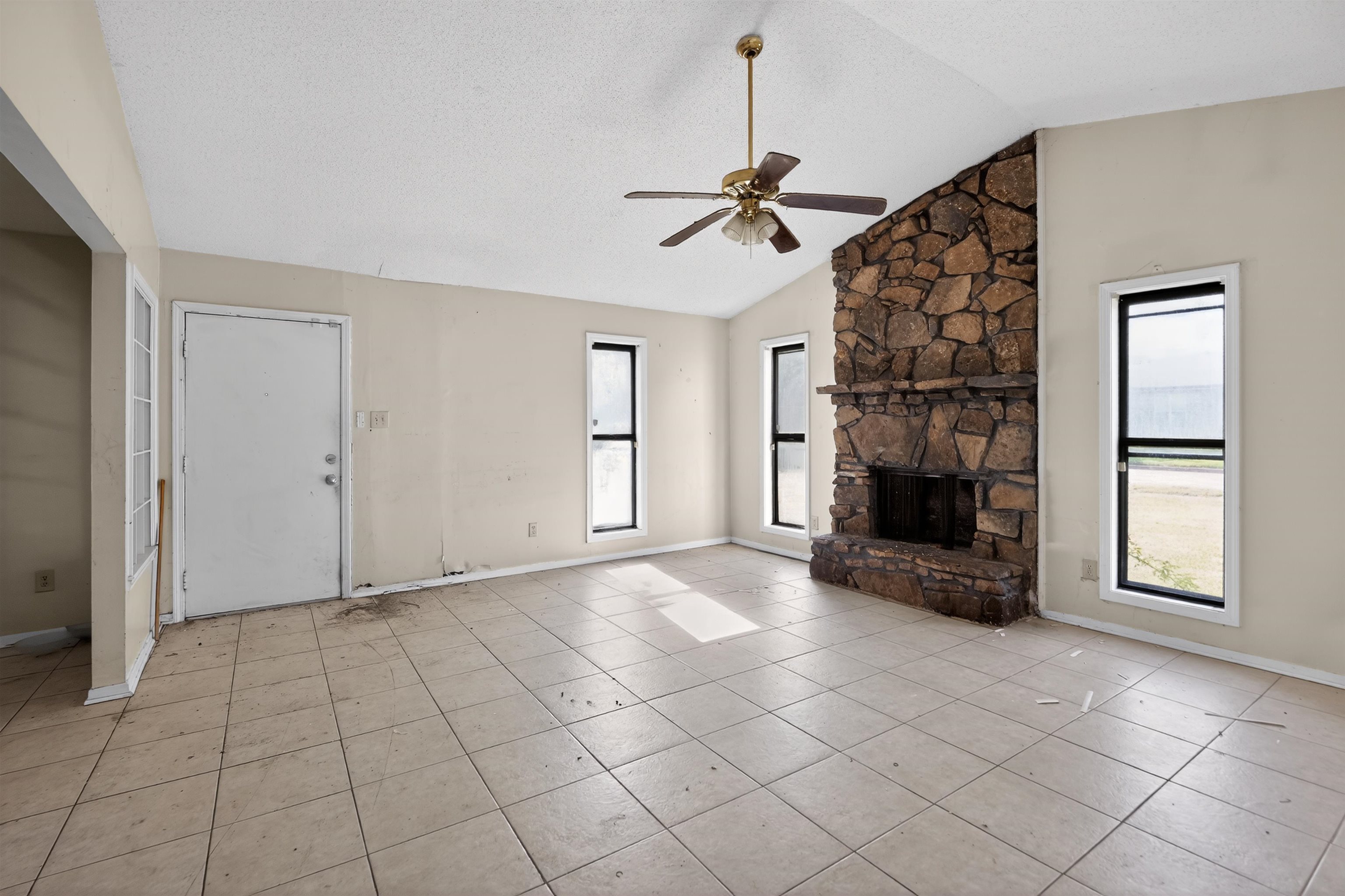 3372 Spring Shadow Drive Memphis, TN 38118 - Photo 14 of 35 Vaulted ceiling living area featuring a prominent stone fireplace, ceiling fan, and tiled flooring
