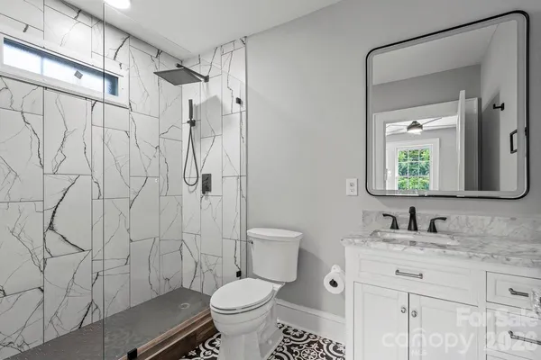 a bathroom with a granite countertop sink toilet a mirror and shower