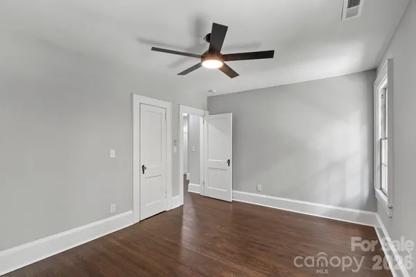 an empty room with wooden floor ceiling fan and windows