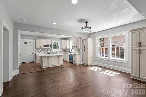 a large white kitchen with window and wooden floor