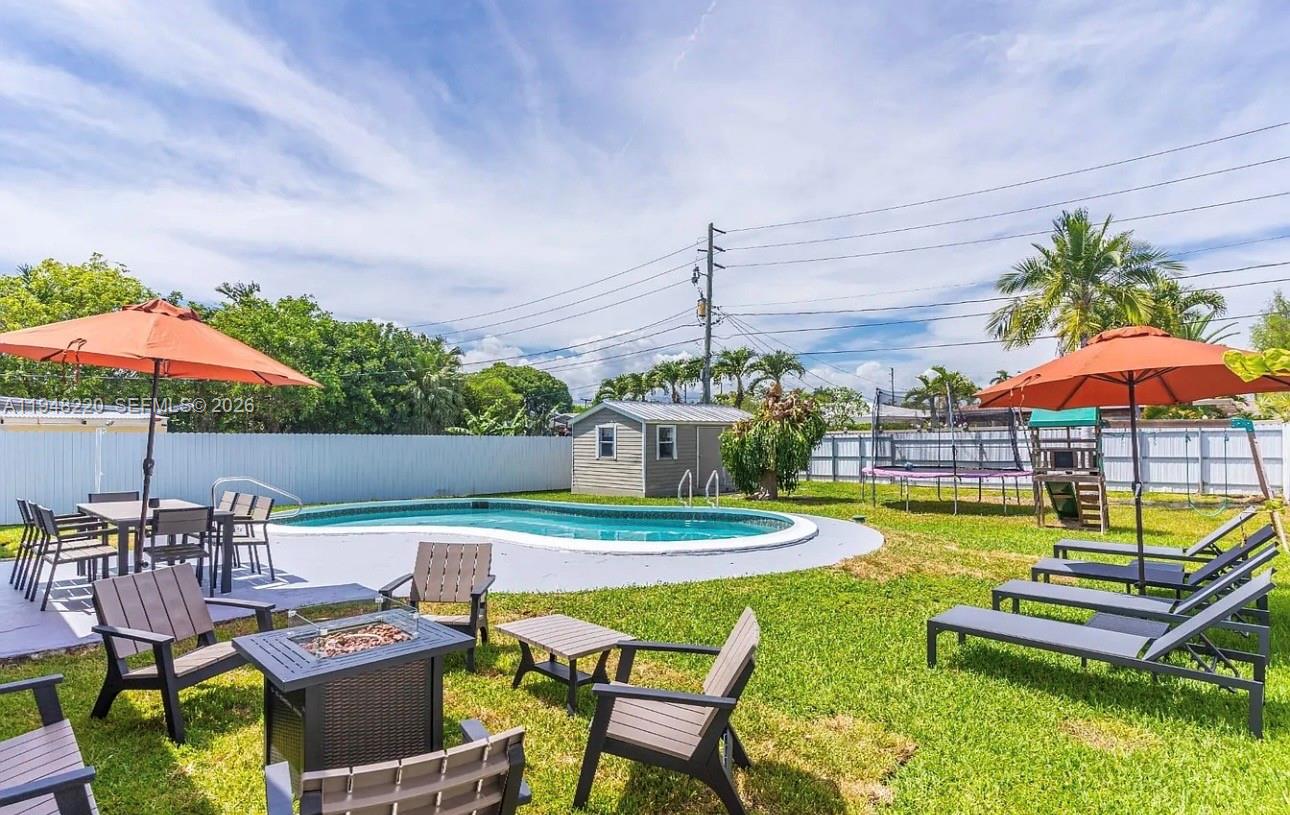 211 Southeast 3rd Street Dania Beach, FL 33004 - Photo 2 of 20 a view of a swimming pool with a table and chairs under an umbrella