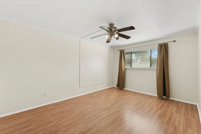 a view of empty room with wooden floor and fan