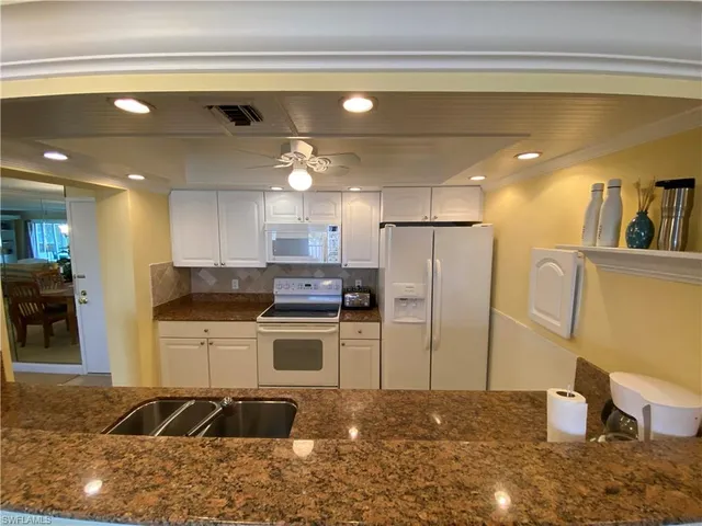 a kitchen with stainless steel appliances kitchen island granite countertop a refrigerator and a stove
