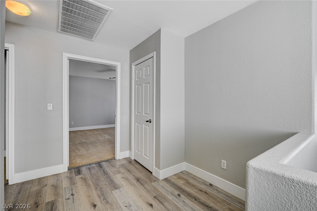7259 Cestrum Road Las Vegas, NV 89113 - Photo 14 of 35 A quiet corridor featuring light wood flooring and a classic paneled door leading to another room.