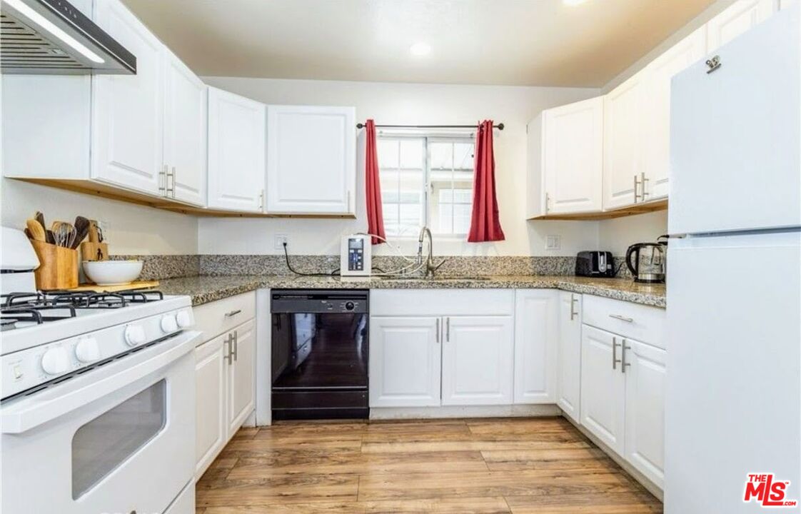 13447 Filmore Street Pacoima, CA 91331 - Photo 4 of 12 a kitchen with granite countertop white cabinets and white appliances