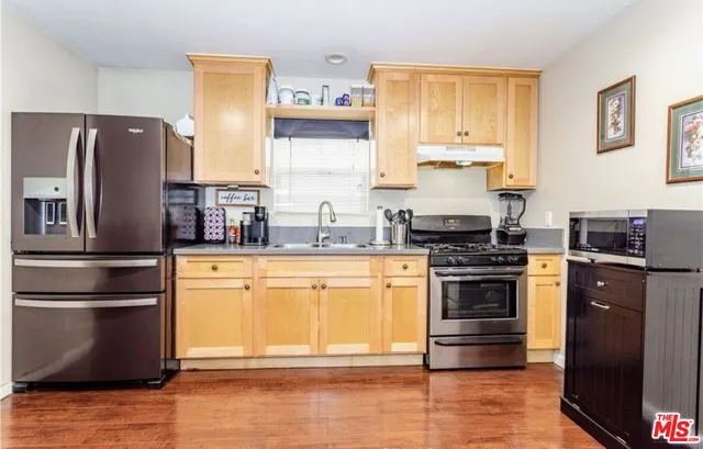 a kitchen with stainless steel appliances granite countertop a refrigerator stove and sink