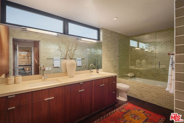 a bathroom with a double vanity sink toilet mirror and bathtub