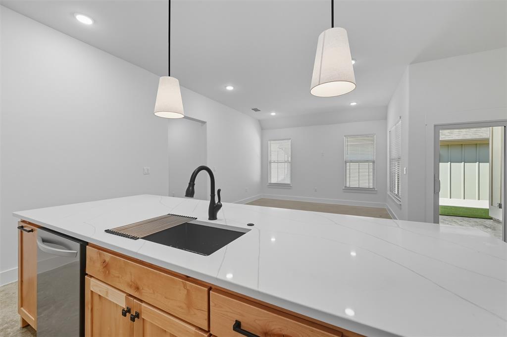 102 Cardinal Wds Granbury, TX 76049 - Photo 36 of 36 Kitchen featuring hanging light fixtures, recessed lighting, open floor plan, light stone countertops, and light brown cabinetry