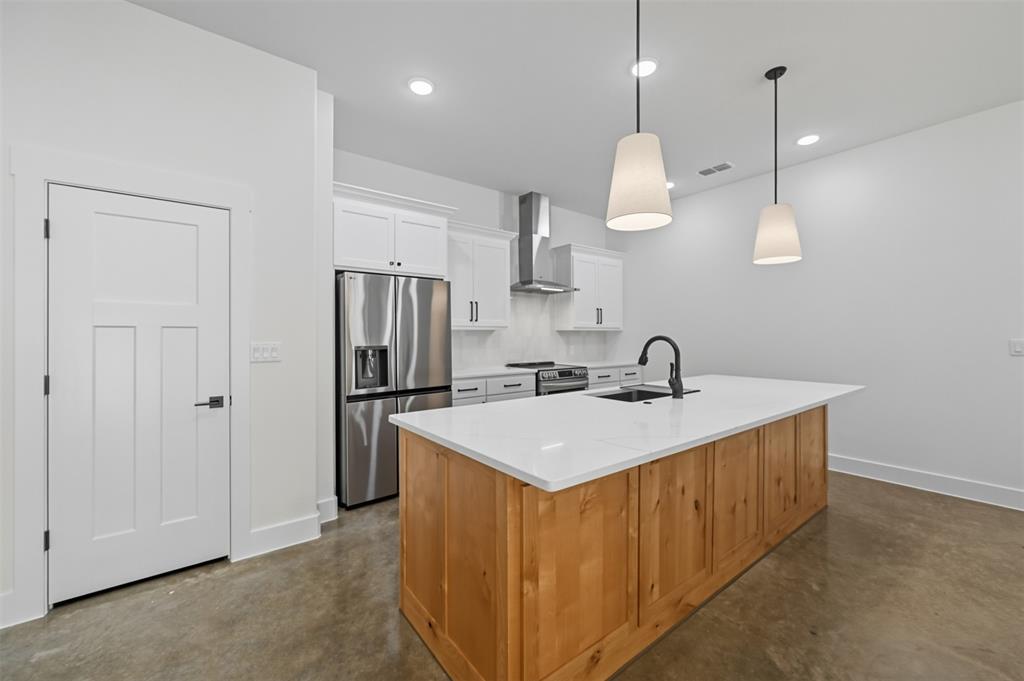 102 Cardinal Wds Granbury, TX 76049 - Photo 8 of 36 Kitchen featuring white cabinetry, appliances with stainless steel finishes, concrete floors, hanging light fixtures, and an island with sink