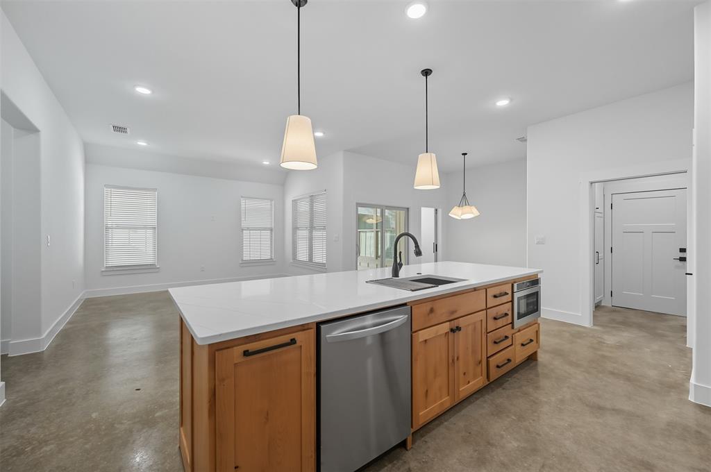 102 Cardinal Wds Granbury, TX 76049 - Photo 9 of 36 Kitchen featuring finished concrete floors, dishwasher, pendant lighting, a center island with sink, and recessed lighting