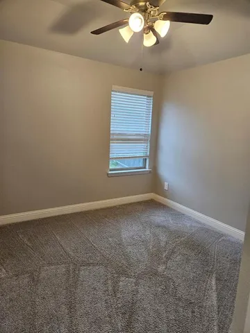 an empty room with a chandelier fan and windows