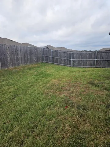 a view of a backyard with grass and wooden fence