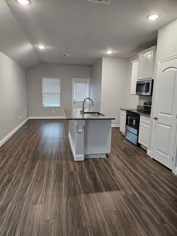 a kitchen with kitchen island wooden floors and stainless steel appliances