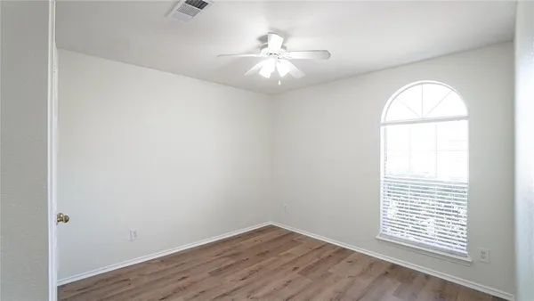 an empty room with wooden floor and fan