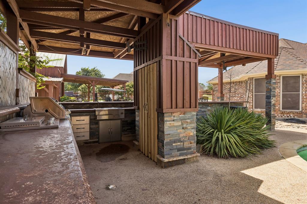 317 Singing Quail Trail Haslet, TX 76052 - Photo 28 of 32 Covered outdoor kitchen featuring a built-in grill, stainless steel cabinetry, stone veneer accents, and a concrete countertop
