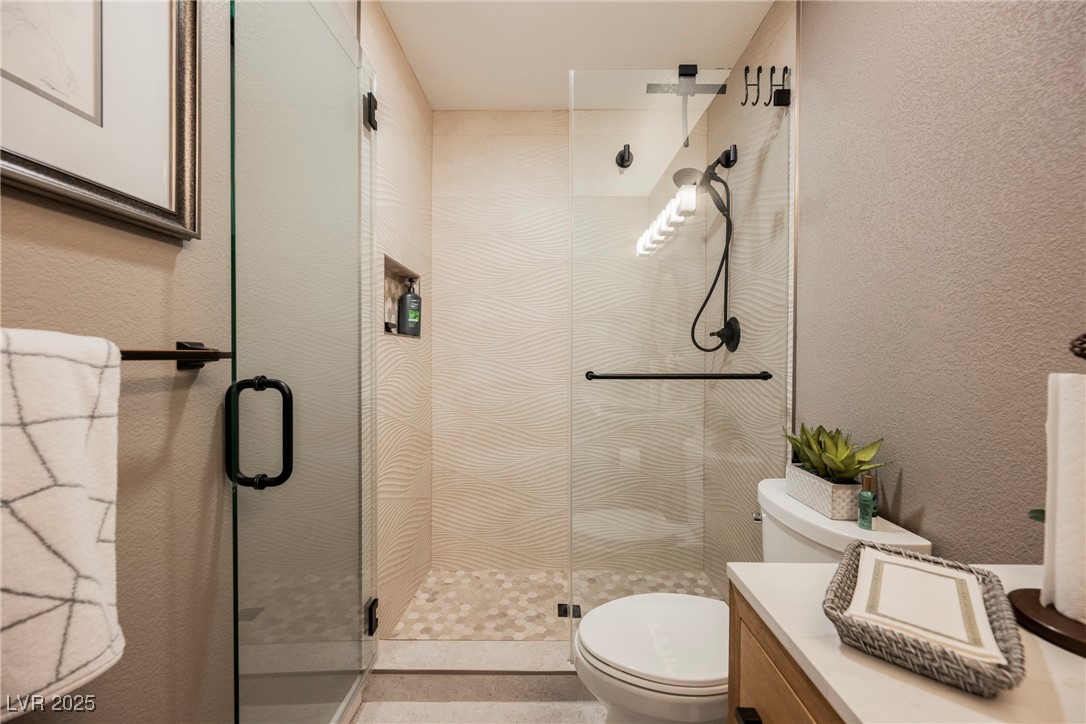 7625 Rolling View Drive, Unit 202 Las Vegas, NV 89149 - Photo 19 of 28 Full bathroom with a textured wall, vanity, and a shower stall