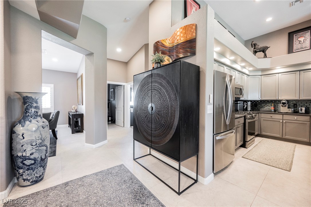 7625 Rolling View Drive, Unit 202 Las Vegas, NV 89149 - Photo 5 of 28 Kitchen featuring appliances with stainless steel finishes, backsplash, dark countertops, light tile patterned floors, and recessed lighting