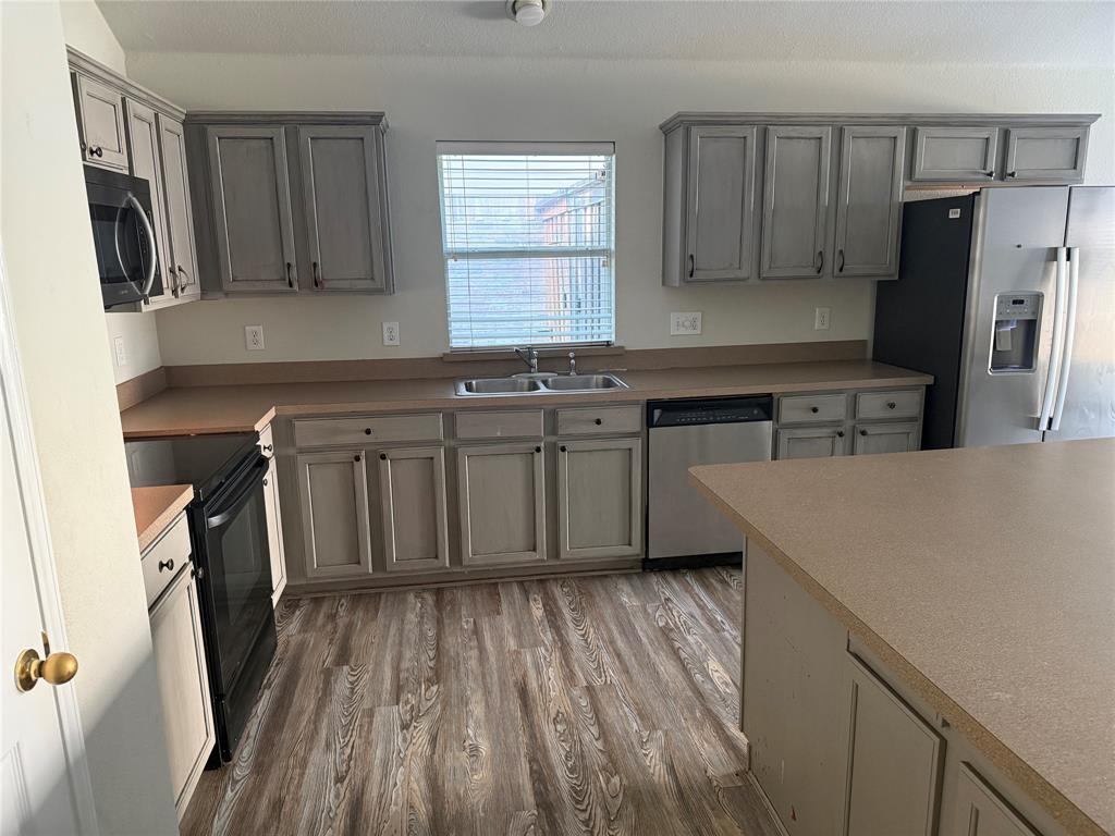 13252 Ridgepointe Road Fort Worth, TX 76244 - Photo 4 of 9 a kitchen with stainless steel appliances a refrigerator a sink a stove a microwave and wooden floors