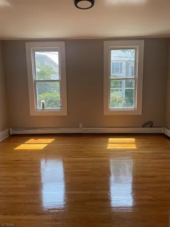 a view of empty room with window and wooden floor